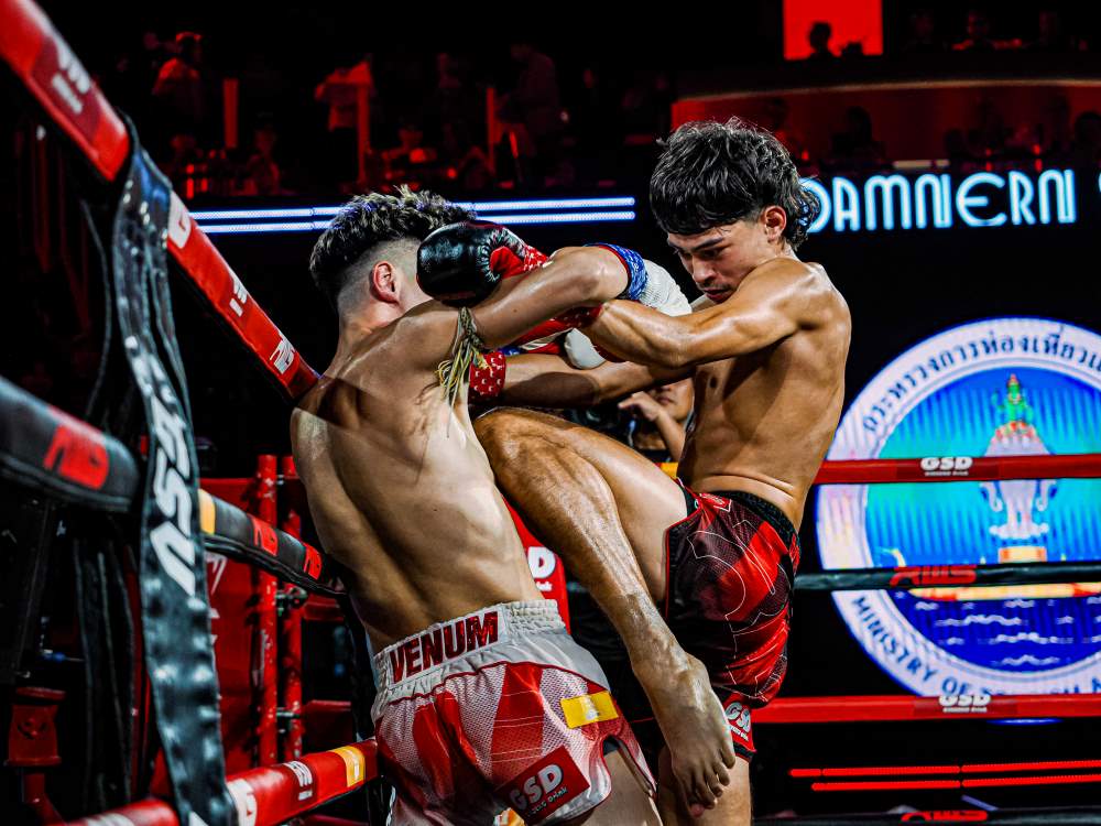 Muay thai fighter delivers a knee strike to his opponent’s chest while in a clinch hold