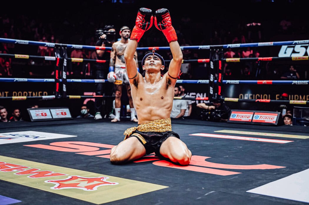 Male Muay Thai fighter raises his gloves in the air as part of the wai kru ceremony