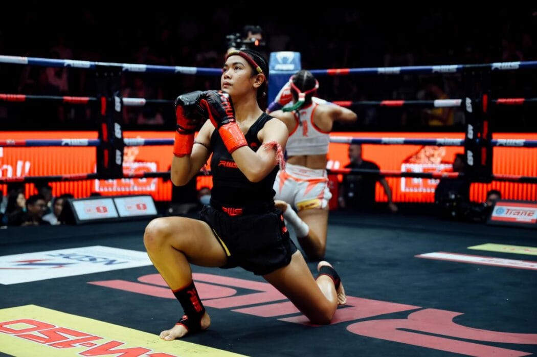 Female fighter during a Wai Kru ceremony demonstrating how to build muscle for women