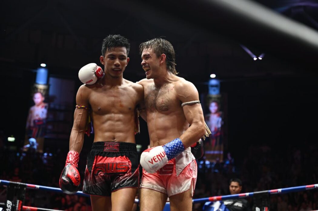 two Muay Thai fighters stand tall and upright after a fight